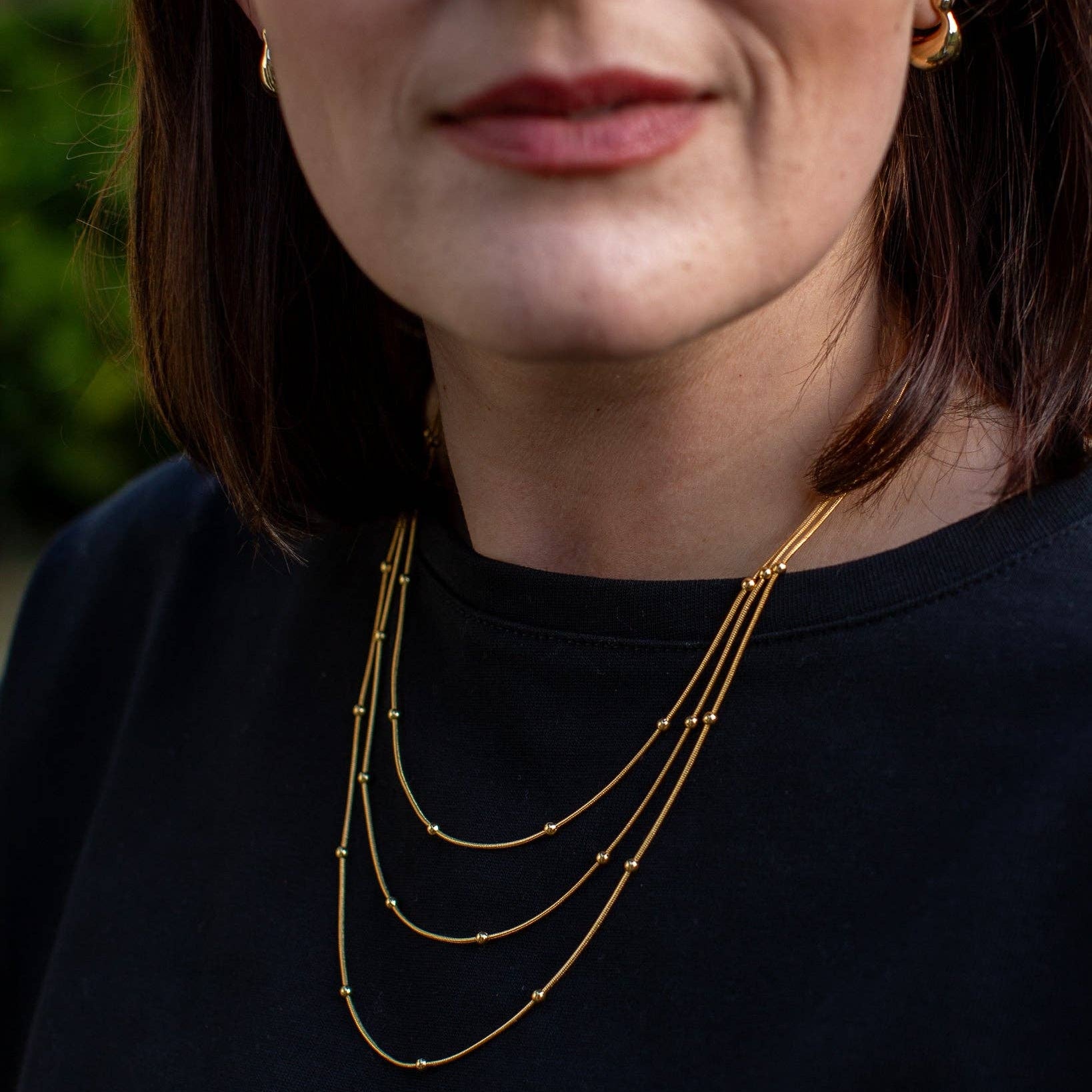 Close-up of a person wearing a gold necklace with a blurred background