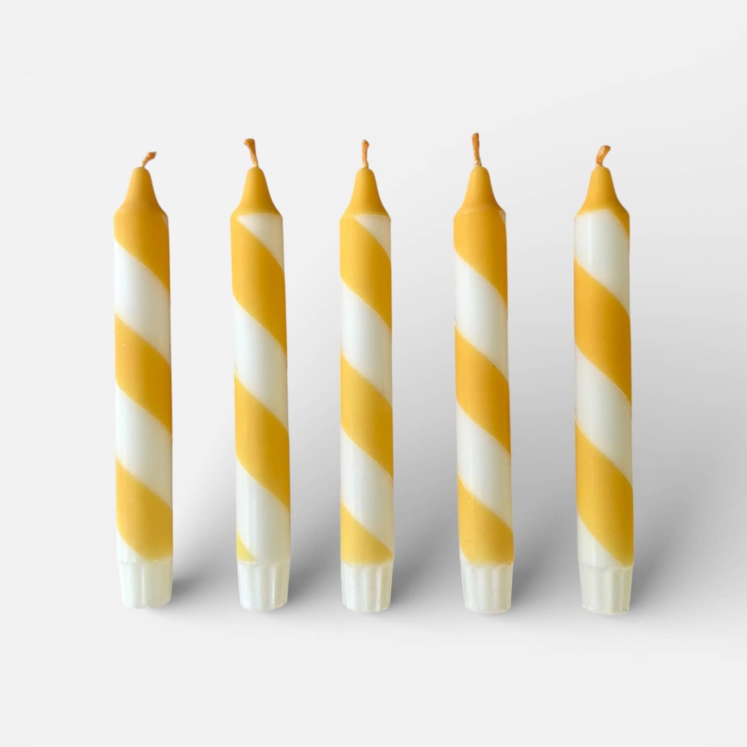 Five yellow and white striped candles on a white background