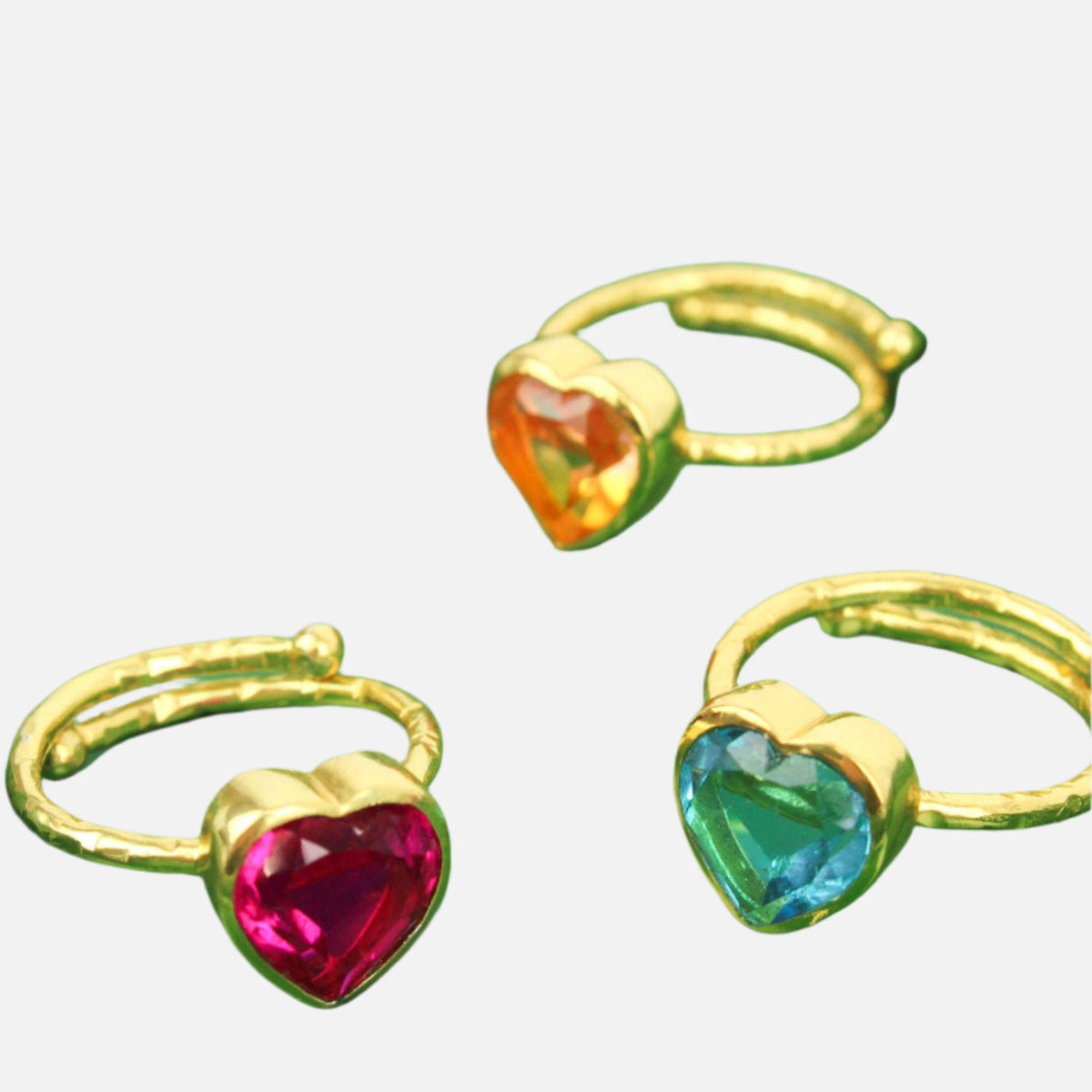 Three gold rings with heart-shaped gemstones on a green and gold star-shaped tray.