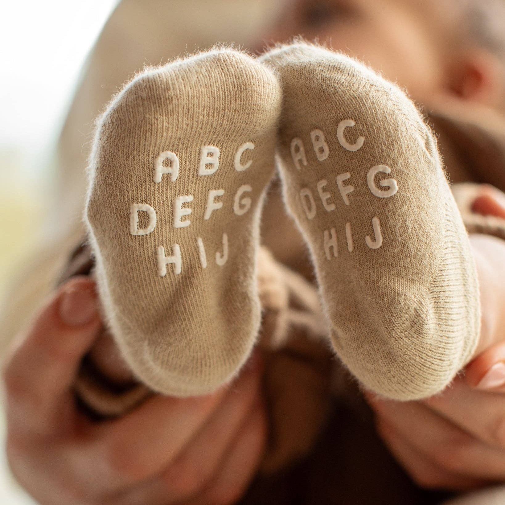 Baby's feet wearing socks with letters held by a person