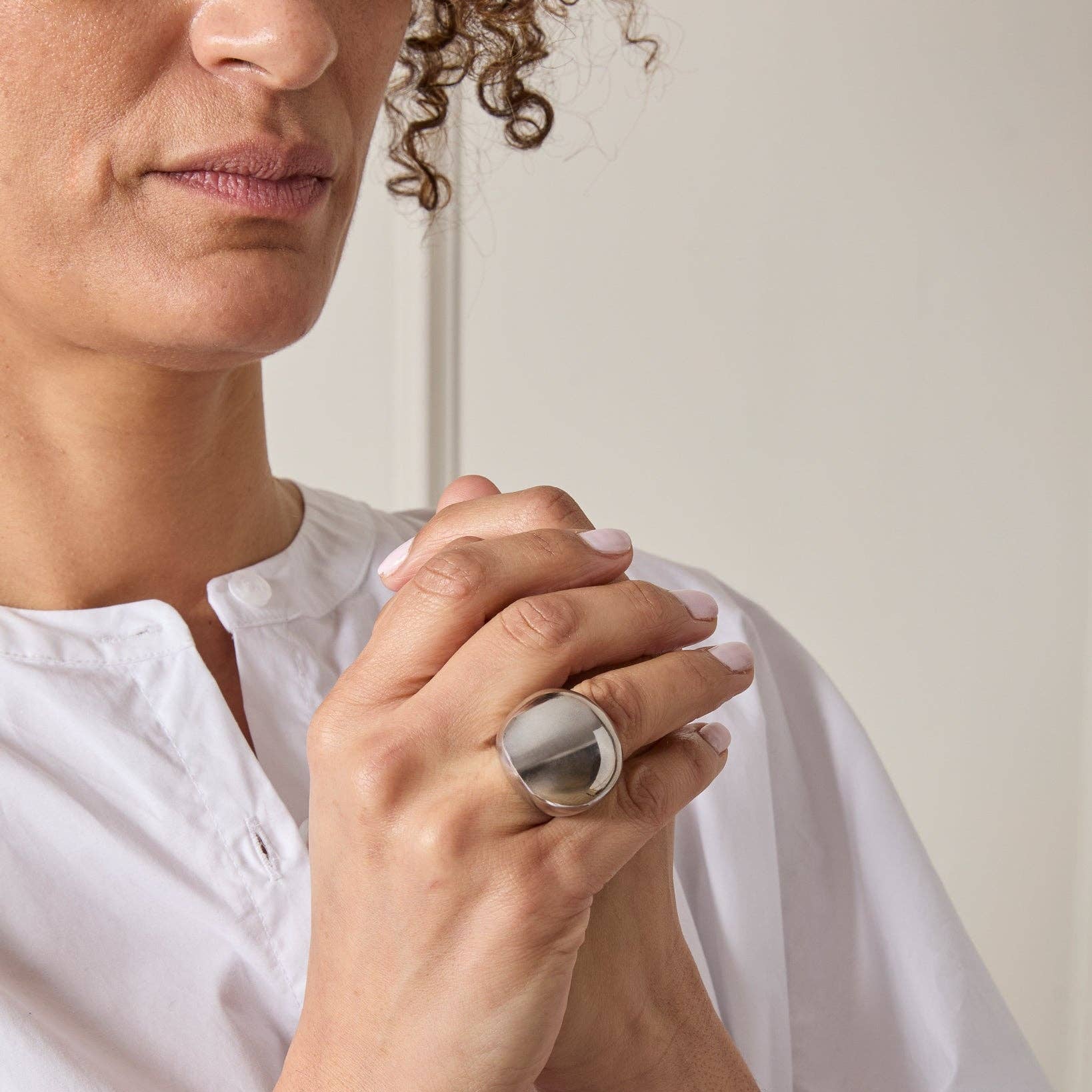 Person wearing a large silver ring with a plain background