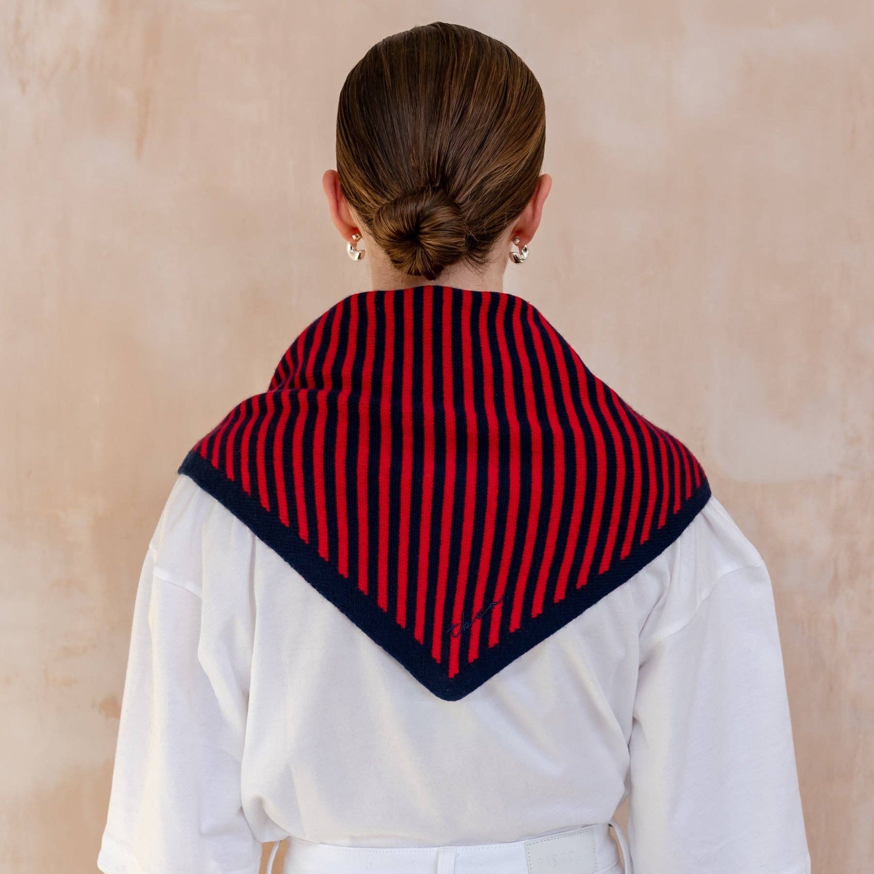 Person wearing a red and navy striped scarf on a beige background