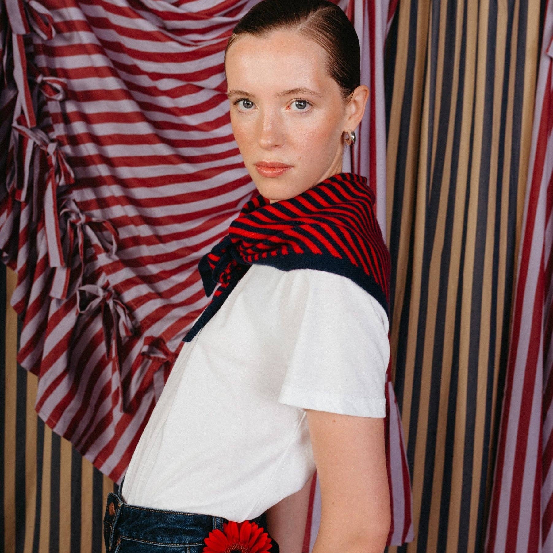 Person wearing a white shirt with a red and navy patterned scarf