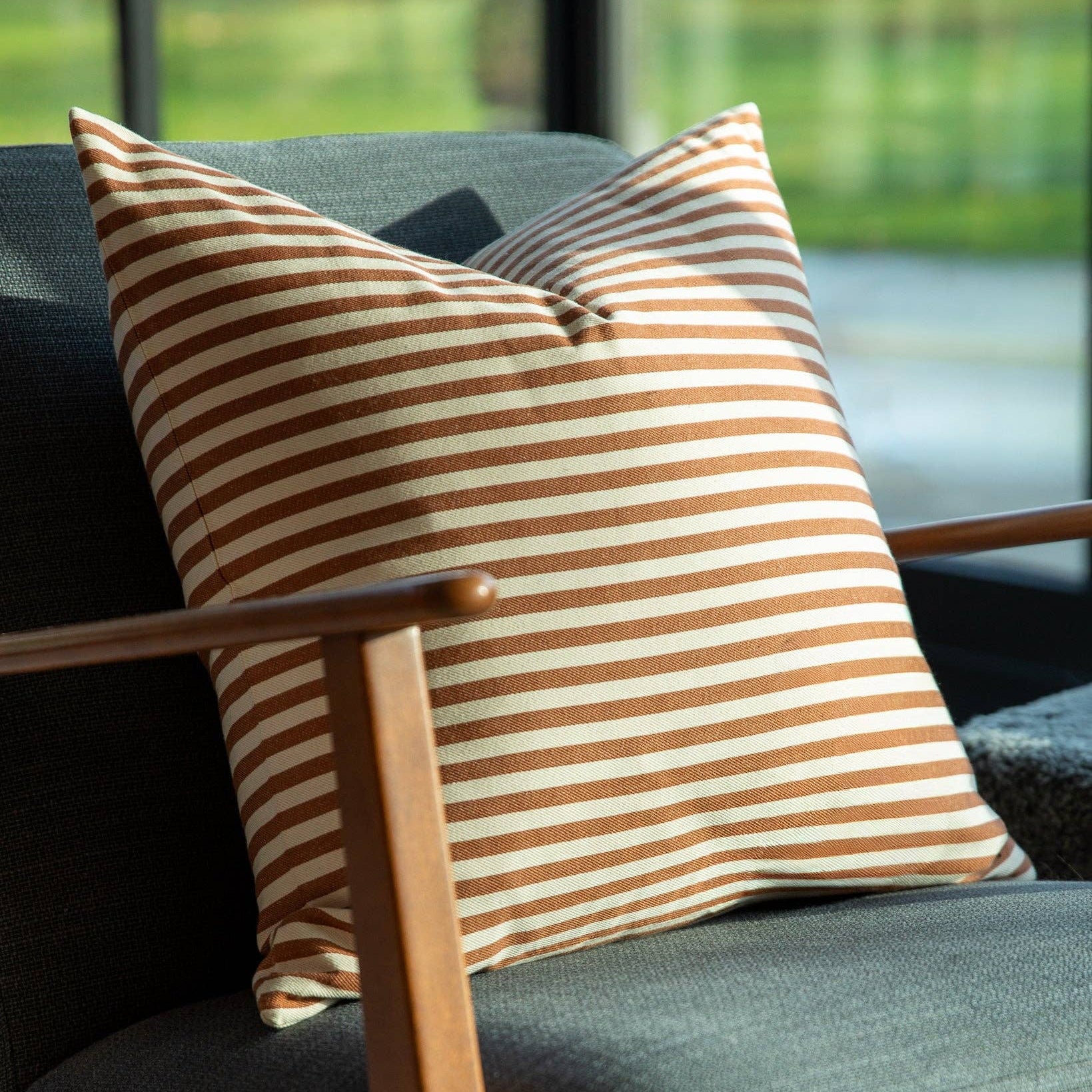 Striped pillow on a dark gray sofa with a blurred outdoor background