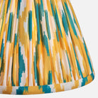 Close-up of a pleated fabric with yellow, green, and white pattern on a white background