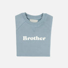 Folded light blue sweatshirt with 'Brother' text on a white background