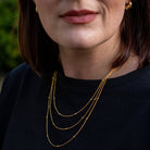 Close-up of a person wearing a gold necklace with a blurred background