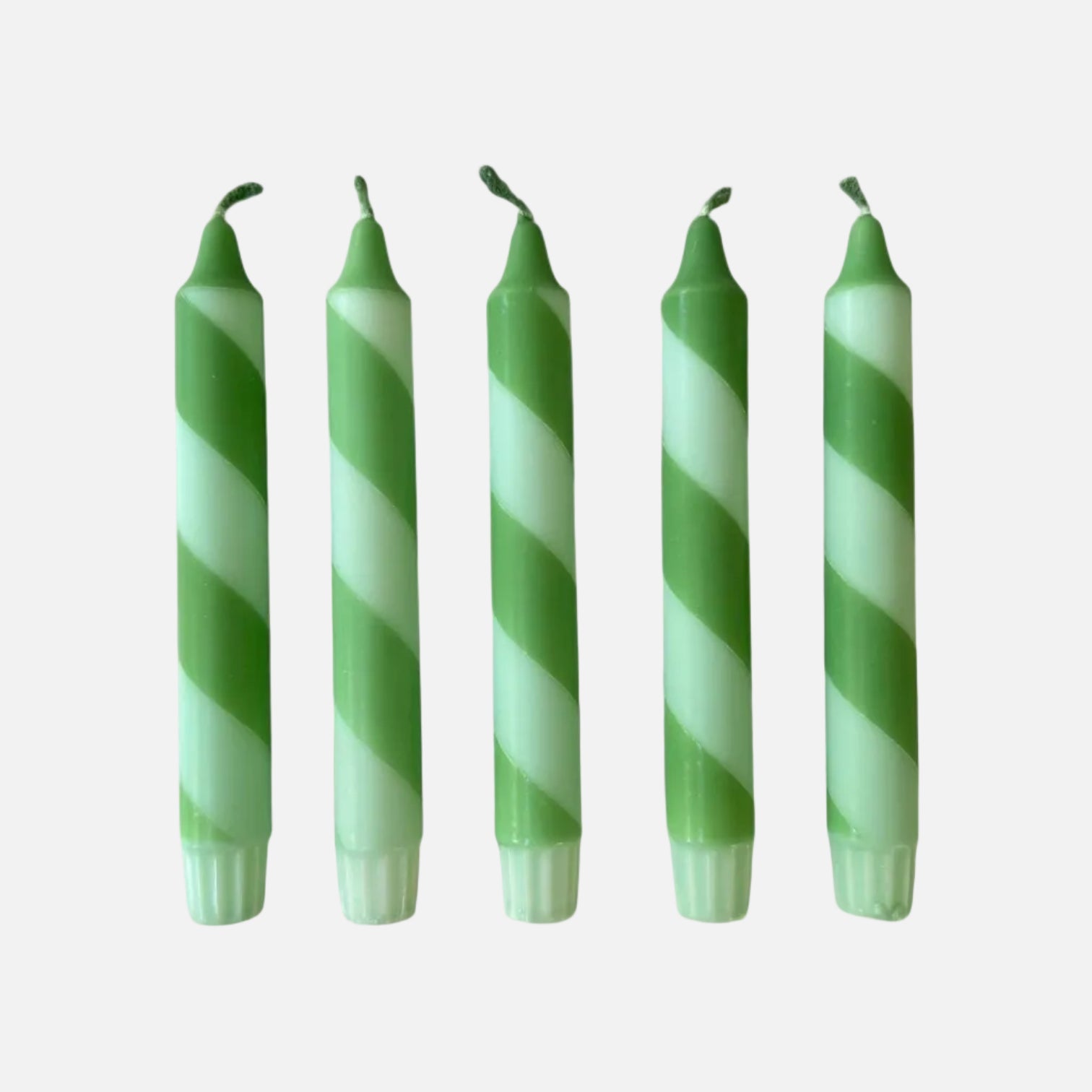 Five green and white striped candles on a light gray background