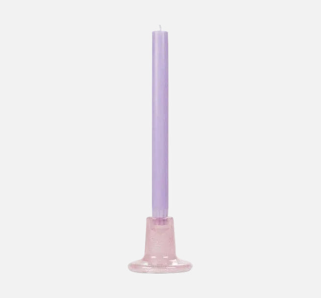 Purple candle on a pink ceramic holder against a white background