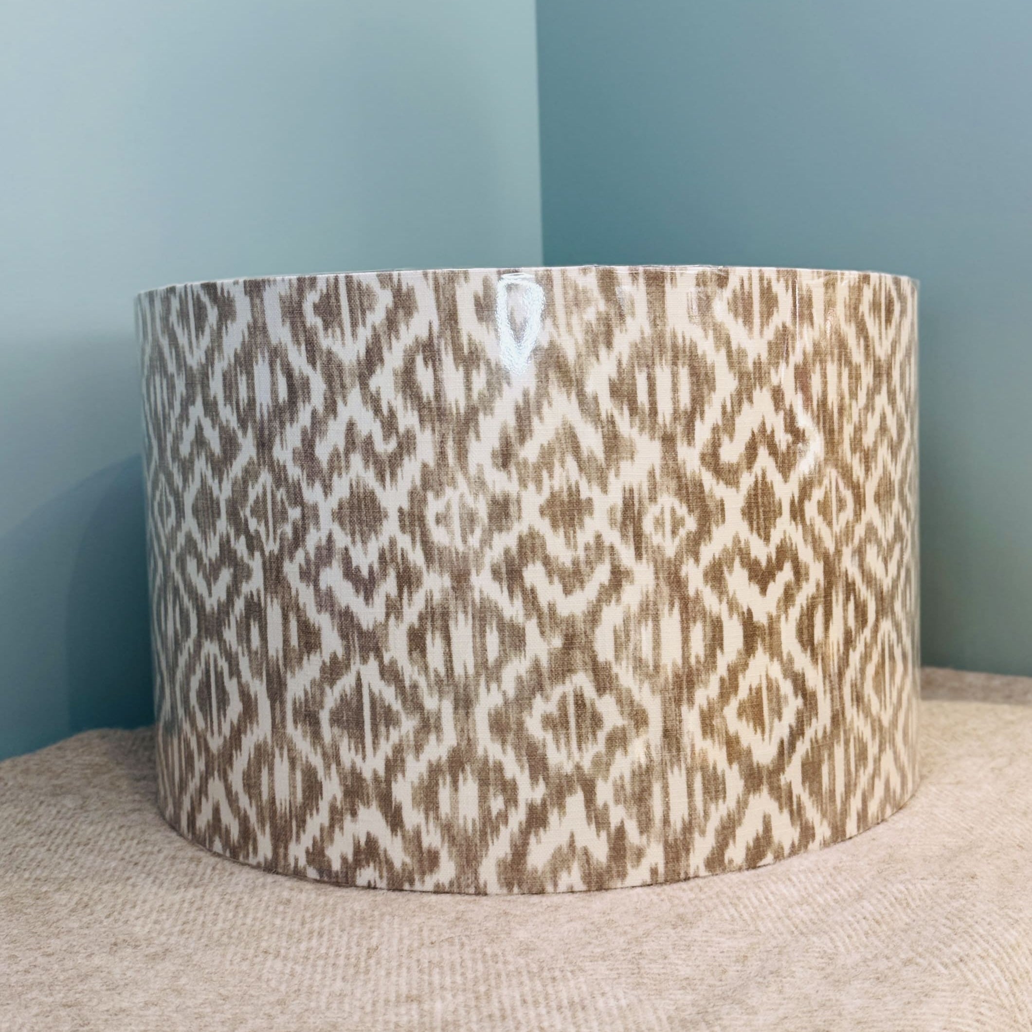 Patterned cylindrical container on a textured surface with a light blue wall in the background
