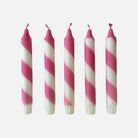 Five pink and white striped candles on a white background