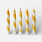 Five yellow and white striped candles on a white background
