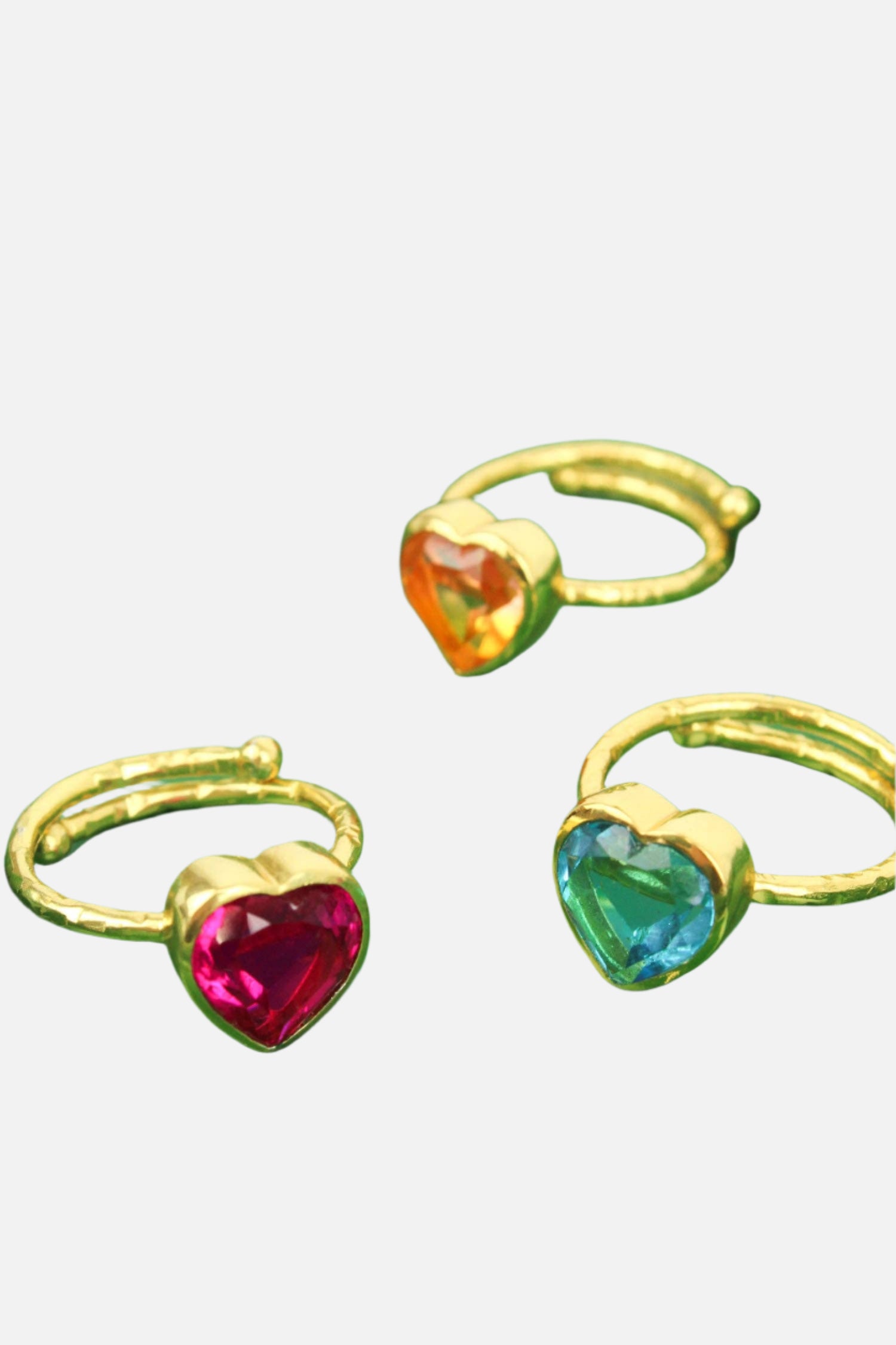Three gold rings with heart-shaped gemstones on a green and gold star-shaped tray.