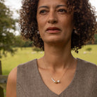 Woman wearing a brown sleeveless top with a necklace in an outdoor setting