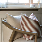 Decorative pillows on a wooden chair with a window and candles in the background