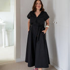 Woman wearing a black dress with white sneakers in a room.