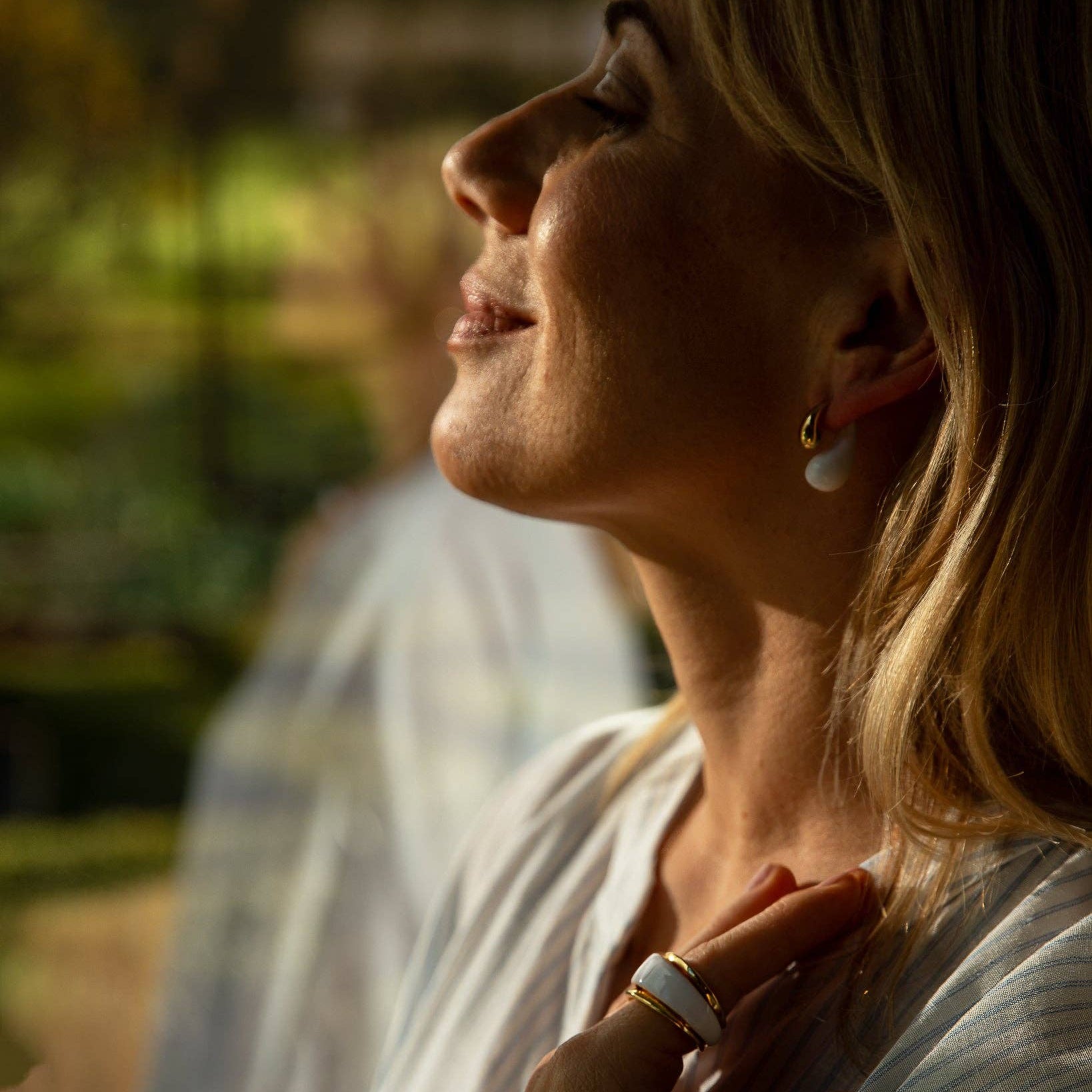 Woman with a ring on her finger, standing outdoors with a blurred background