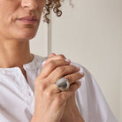 Person wearing a large silver ring with a plain background