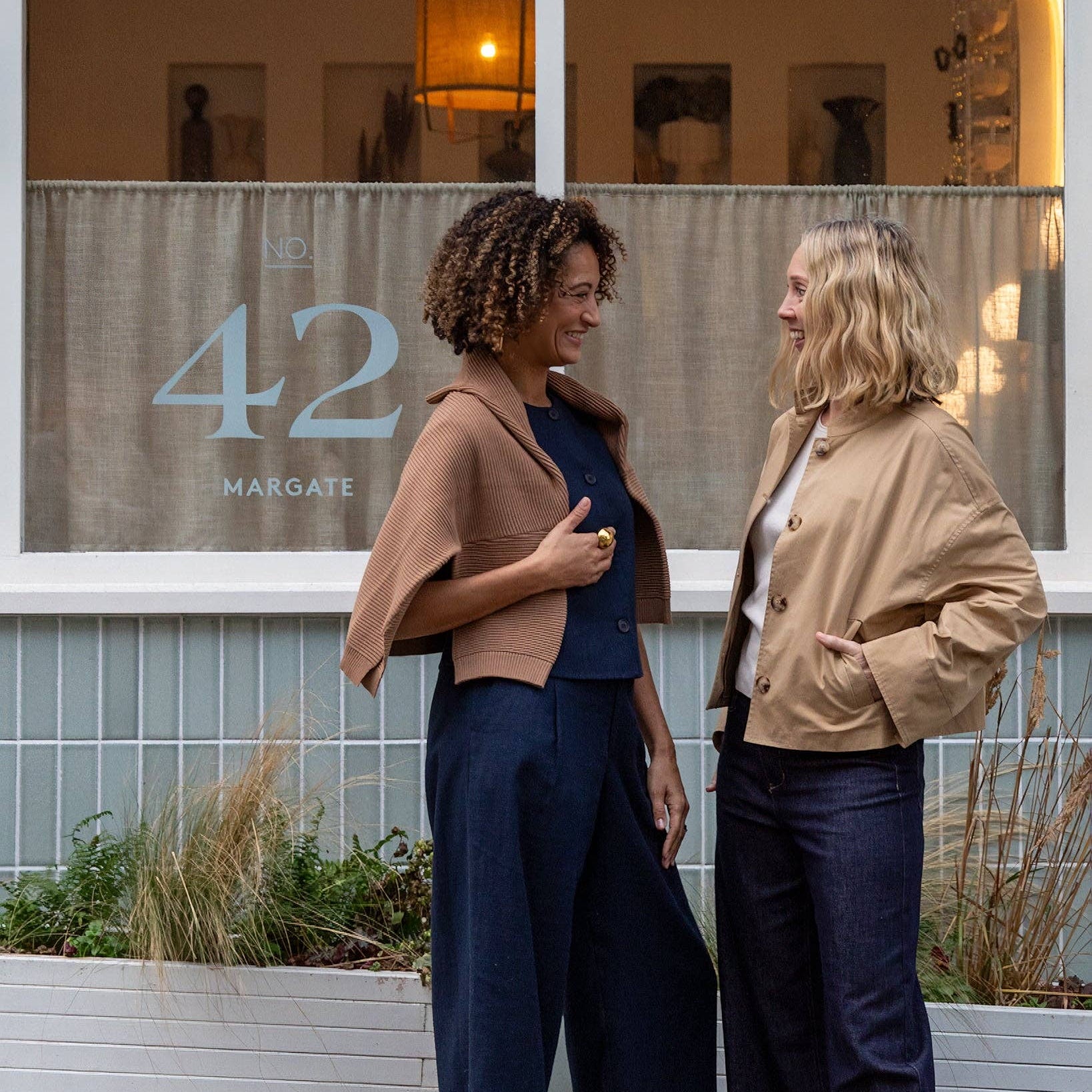 Two women standing outside a building with a sign displaying '42 Margate'.