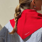 Person wearing a red scarf with 'thema' branding on a striped shirt.