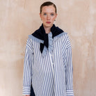 Person wearing a striped shirt with a navy ruffle triangle scarf