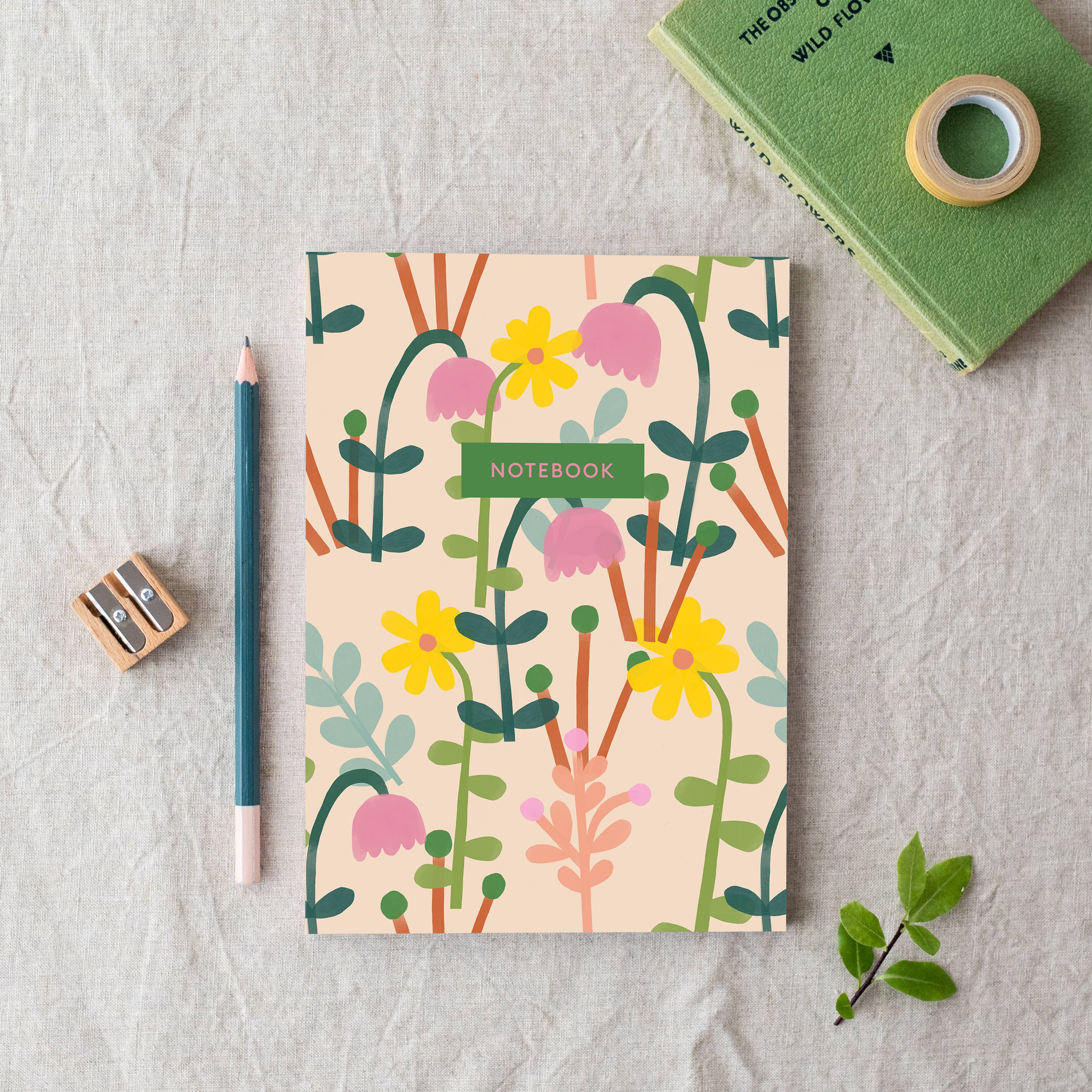 Notebook with floral design on a textured surface with stationery items.
