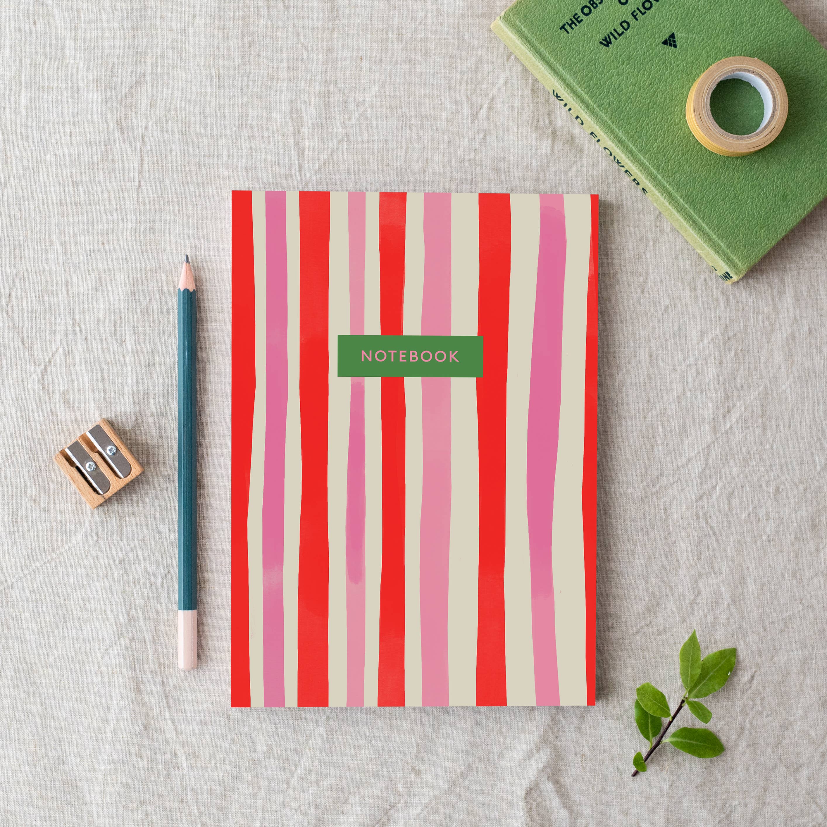 Striped notebook with a pencil, sharpener, and tape on a textured surface