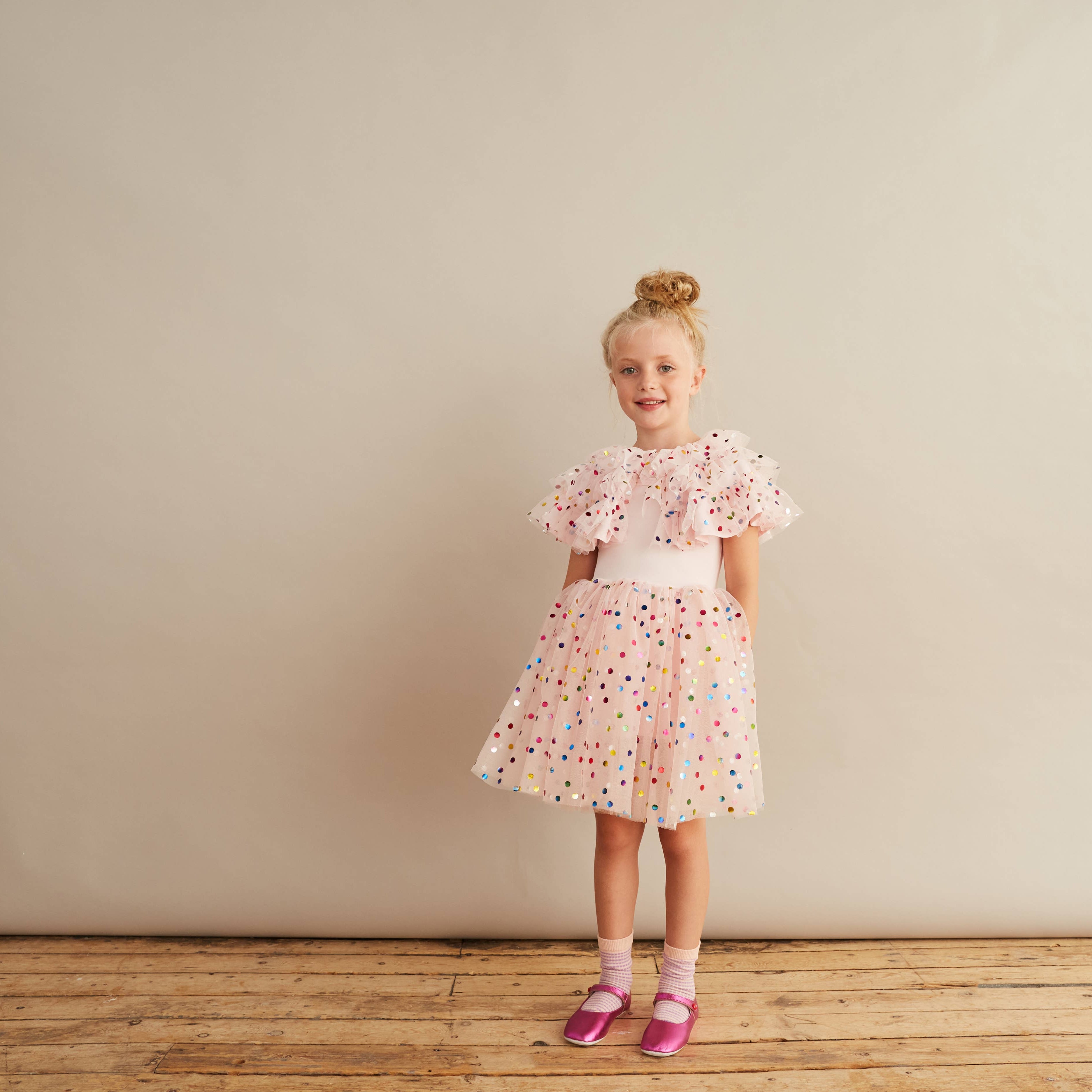 Young girl in a floral dress standing against a plain background