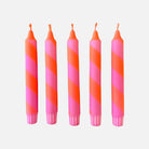 Five pink and orange striped candles on a white background