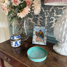 Decorative table with a vase of flowers, a lamp, a photo frame, and a bowl.