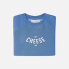 Folded blue sweatshirt with 'Say Cheese' text on a white background